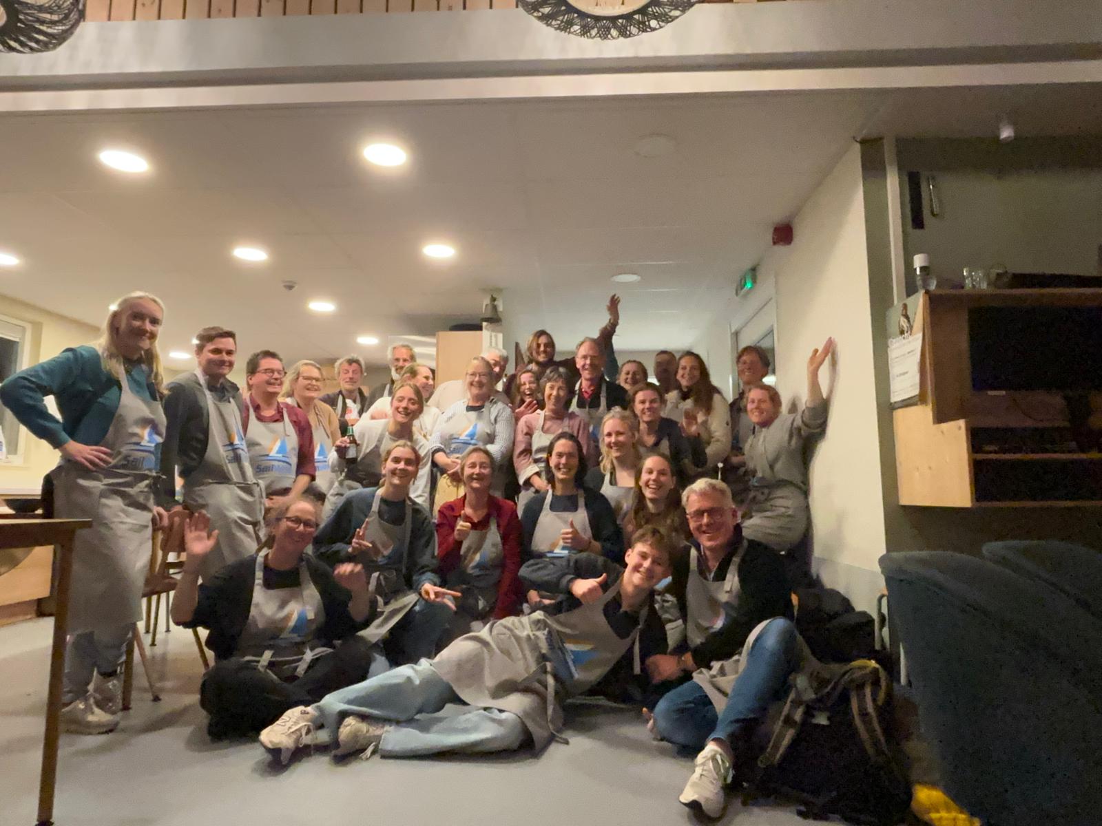 Het team SailWse 2025 staat enthousiast op de foto in de woonkamer op Robinson Cruose.